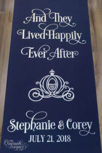 Step into the enchantment of your love story with our 'And They Lived Happily Ever After' custom aisle runner. Hand-painted to perfection, it transforms your aisle into a magical path, inviting you to dance towards your forever. Complete with Cinderella's coach, names & date.